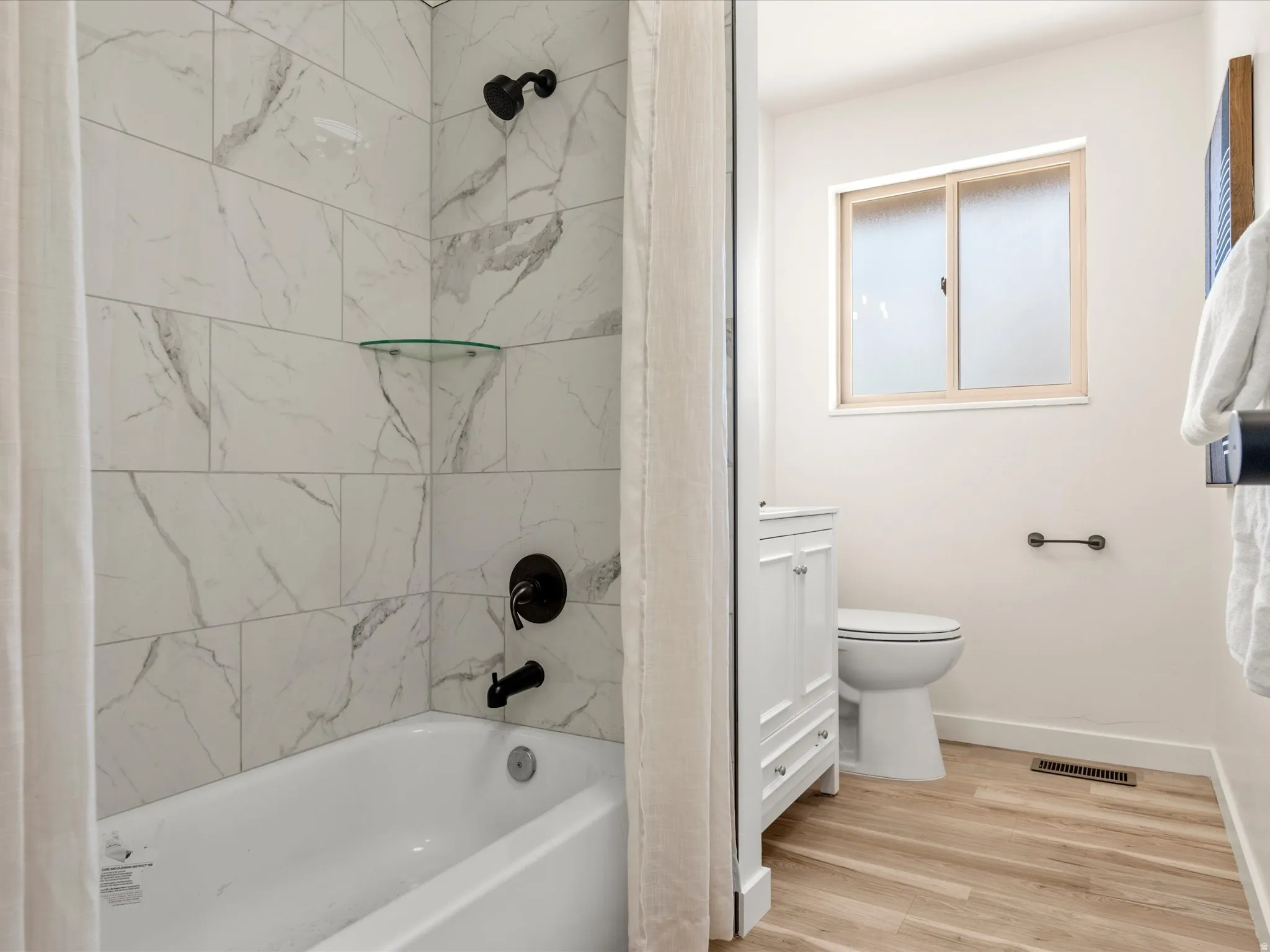 Main Bathroom. White subway tile shower surround with a glass shelf and matte black fixtures