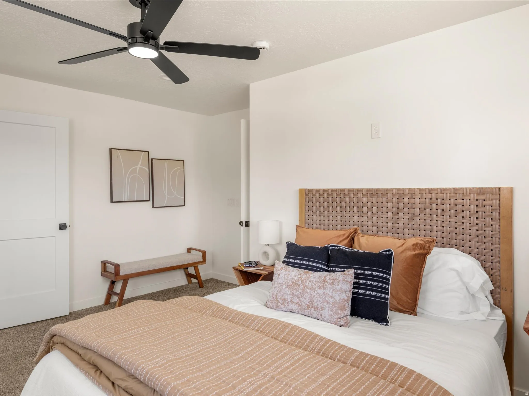 Primary Bedroom. White interior walls, black-finish ceiling fan, white paneled interior door, and a woven headboard