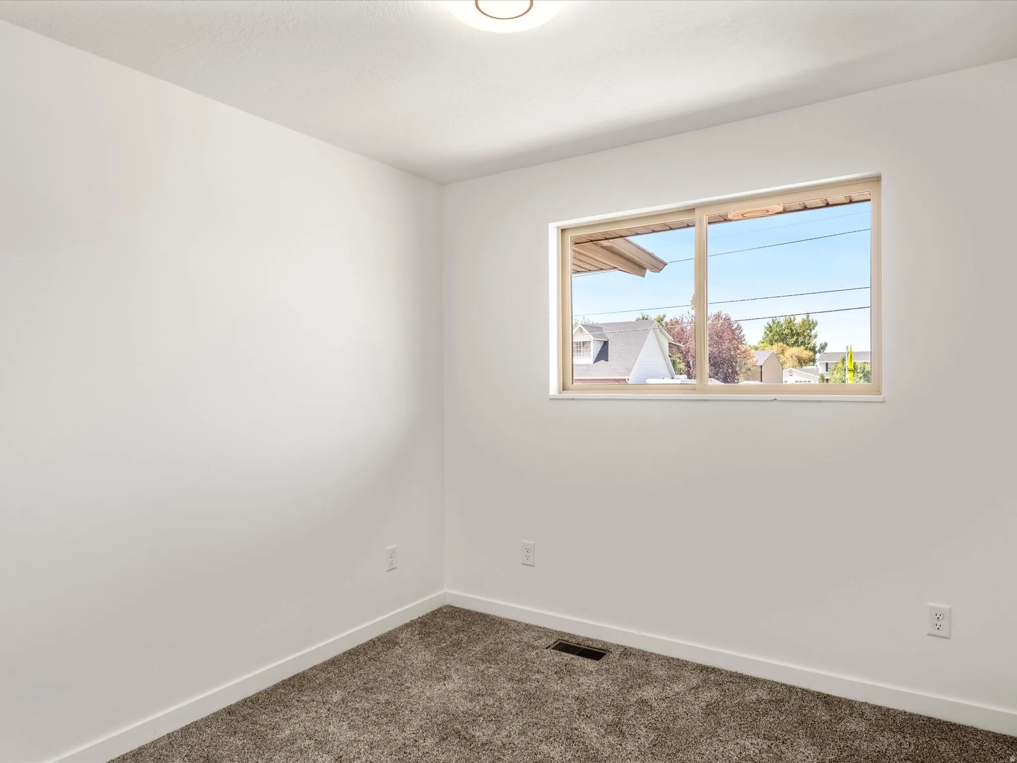 Bedroom #1 upstairs. Neutral wall finishes, carpeted flooring, and a single window with a light-toned frame