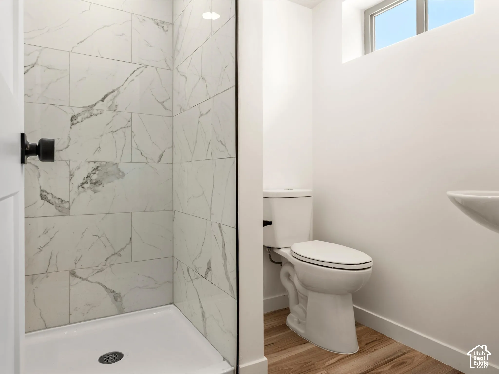 Basement Bathroom. Walk-in shower with white tile surround, glass enclosure, and matte black hardware