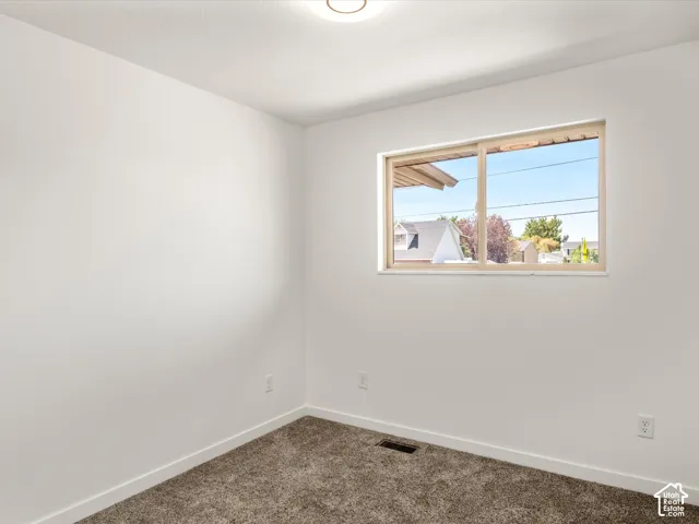 Bedroom #1 upstairs. Neutral wall finishes, carpeted flooring, and a single window with a light-toned frame