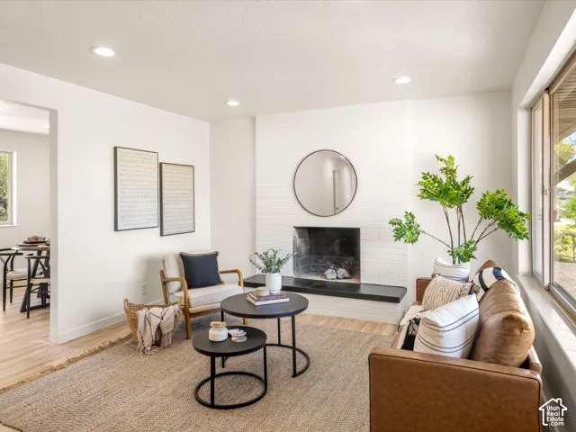 White painted brick fireplace with a dark stone hearth, recessed lighting, and large windows