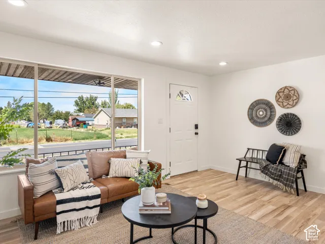 Expansive window, recessed lighting, wood-finish flooring, white entry door with glass insert, and a white wall finish