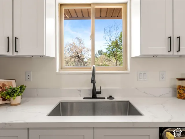 White shaker cabinetry with matte black hardware, undermount stainless steel sink, solid surface countertops, and a single-handle matte black faucet