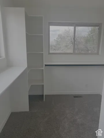 Built-in shelving, integrated desk, and carpeted flooring