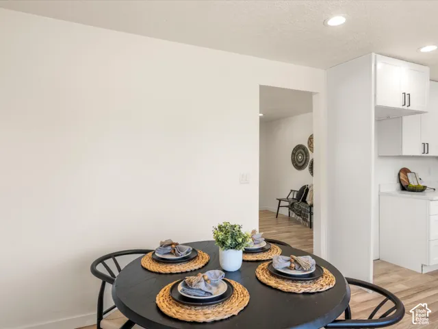 Recessed ceiling lighting, wood-finish flooring, white cabinetry, and light-toned countertops