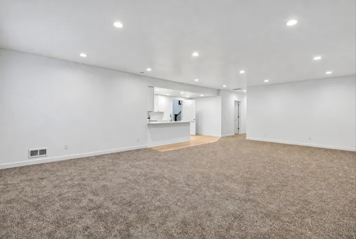 Recessed lighting, white walls, and a pass-through window with a breakfast bar