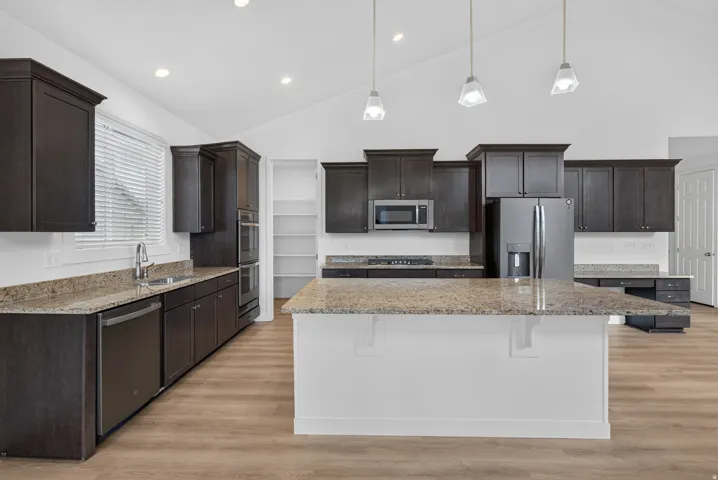 Vaulted ceilings, recessed lighting, wood-finish flooring, dark wood cabinetry, and granite countertops