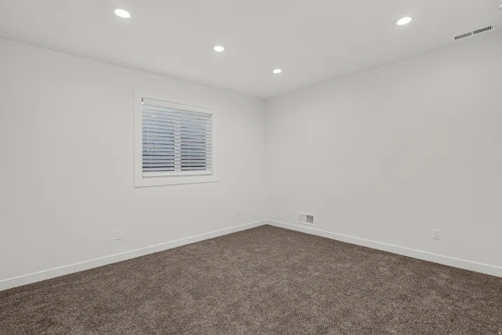 Recessed ceiling lighting, white walls, white window trim, horizontal window blinds, and brown carpet flooring