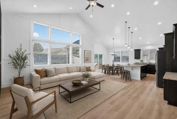 Vaulted ceilings, large picture windows, wood-finish flooring, recessed lighting, and a kitchen island with seating