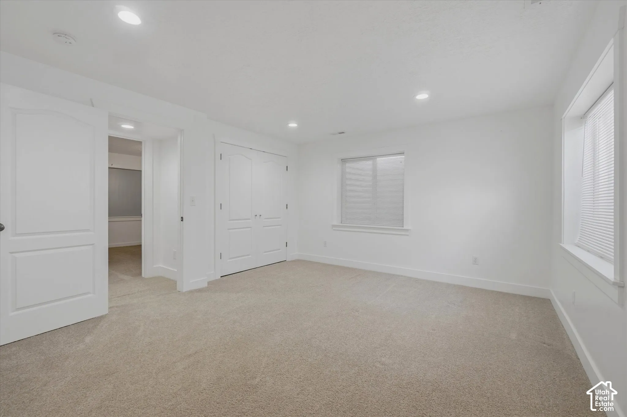 Wall-to-wall carpeting, recessed ceiling lighting, and multiple windows with blinds