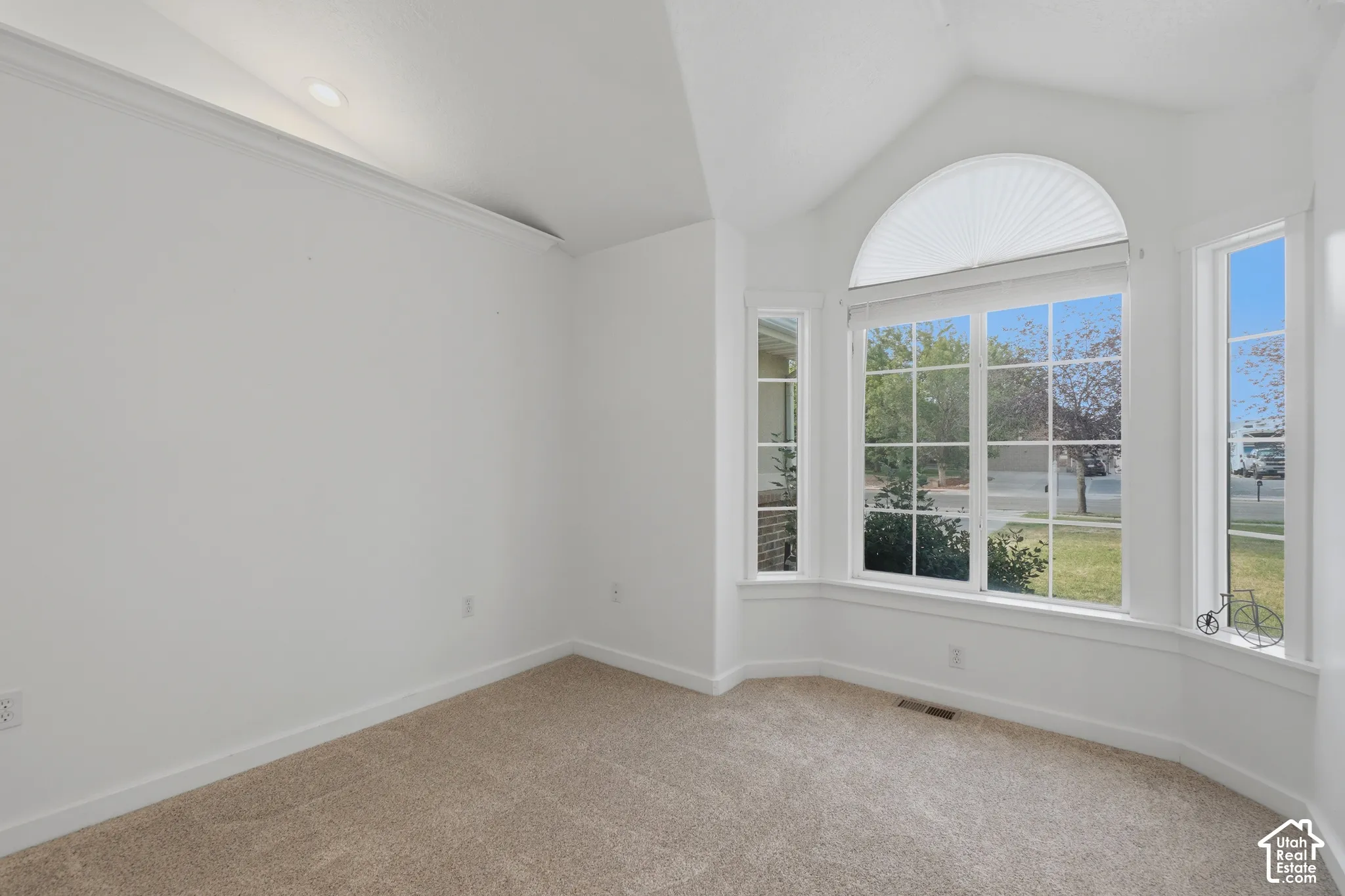 Bay window with arched transom, vaulted ceiling, recessed lighting, and neutral carpet