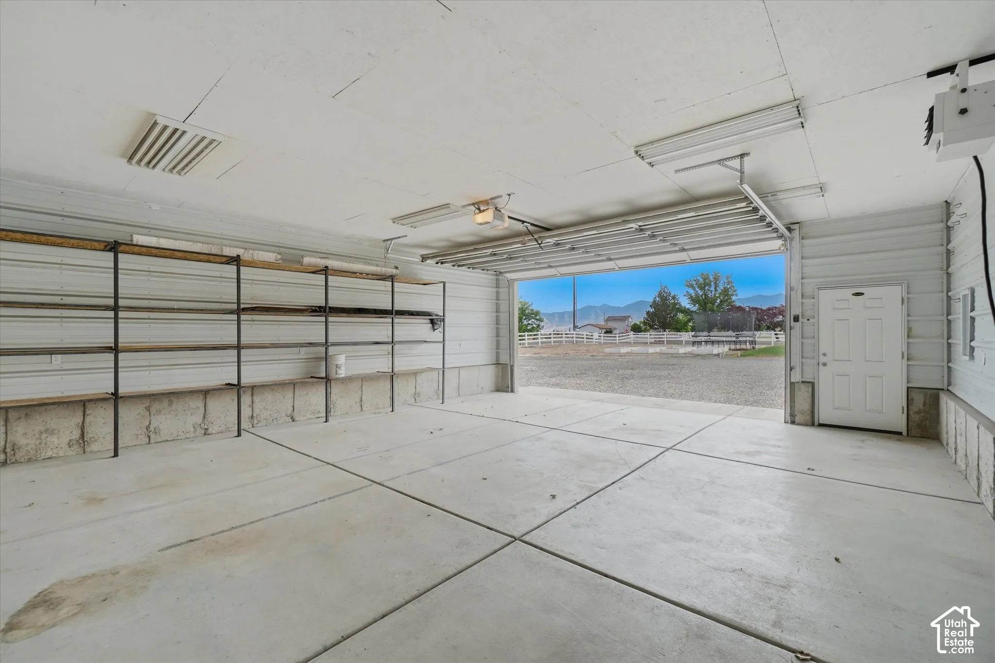 Garage with concrete flooring, built-in shelving, and a side-entry door