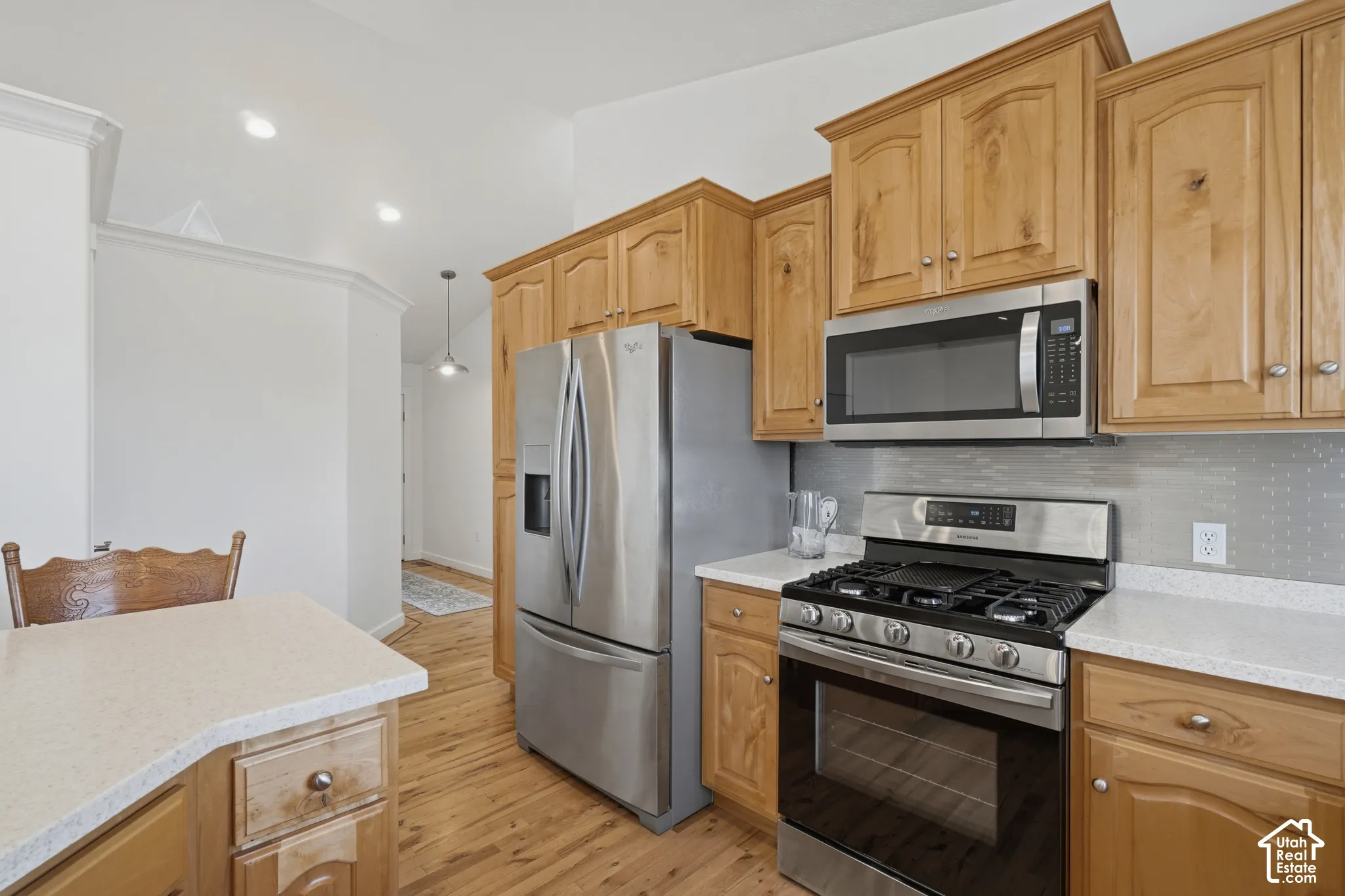 Kitchen featuring wood cabinetry, stainless steel appliances, light-toned countertops, and wood-finish flooring