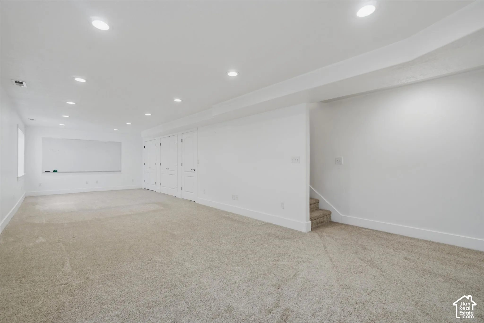 Expansive room with recessed lighting, light-toned carpet, white walls, and multiple white panel doors