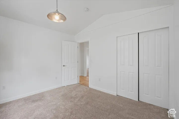 Carpeted room featuring a white interior door, a two-panel sliding closet door, and a metal pendant light fixture