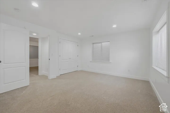 Wall-to-wall carpeting, recessed ceiling lighting, and multiple windows with blinds
