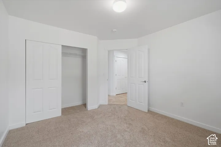 Neutral tone wall paint, flush mount ceiling light, carpet flooring, bi-fold closet doors, and interior door with hardware
