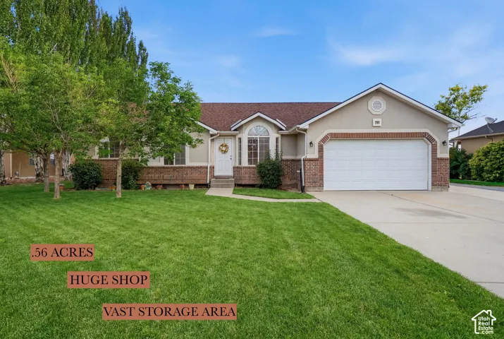 Single-level exterior featuring a stucco and brick facade, an attached two-car garage, arched window detailing, and a shingled roofline