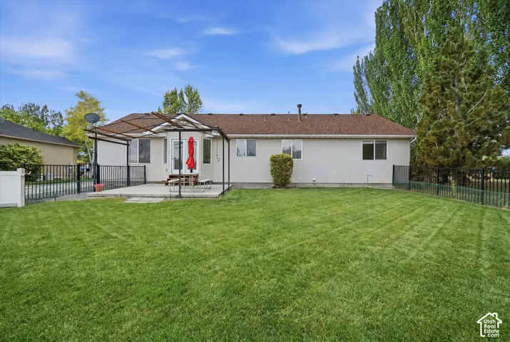 Expansive backyard with a manicured lawn, concrete patio, and a pergola structure