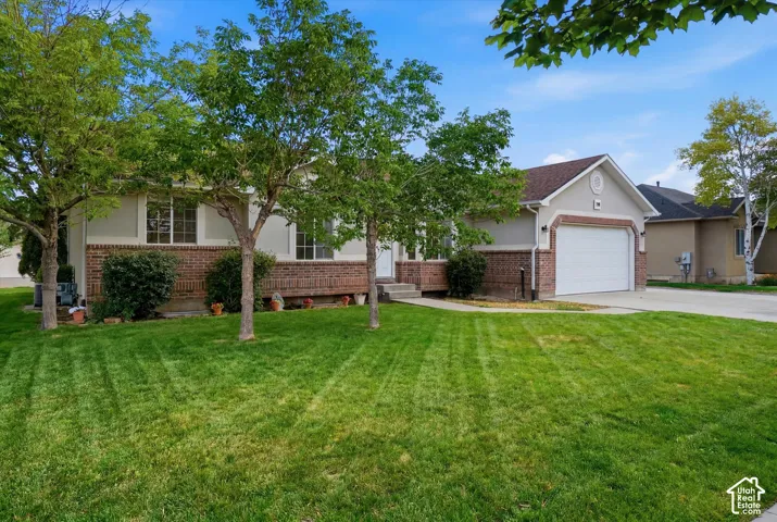 Stucco and brick exterior with a pitched roof, an attached garage, and a concrete driveway