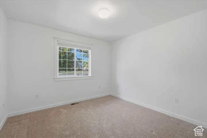 Neutral wall finishes, carpeted flooring, and a single window