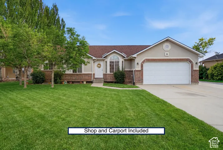 Single-story exterior featuring a brick and stucco facade, arched window detailing, attached garage, and manicured lawn