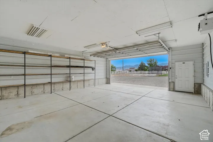 Garage with concrete flooring, built-in shelving, and a side-entry door