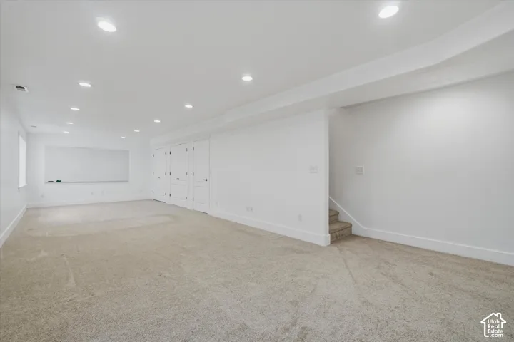 Expansive room with recessed lighting, light-toned carpet, white walls, and multiple white panel doors