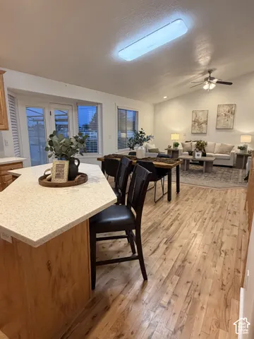 Kitchen island with a speckled countertop, wood-finish flooring, vaulted ceiling, and recessed lighting
