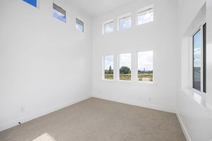 Soaring ceilings, multiple windows, and light-toned carpeting