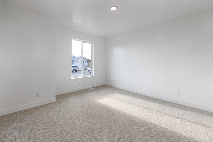 Recessed lighting, light-toned carpeting, white walls, and a large window