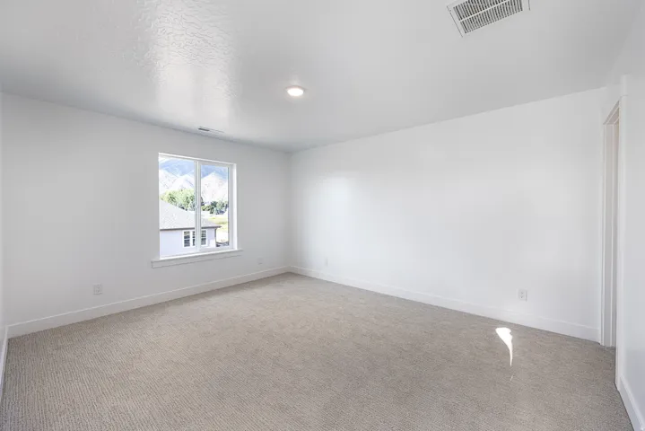 Recessed ceiling light, white walls, light-colored carpeting, white window frame, and mountain scenery