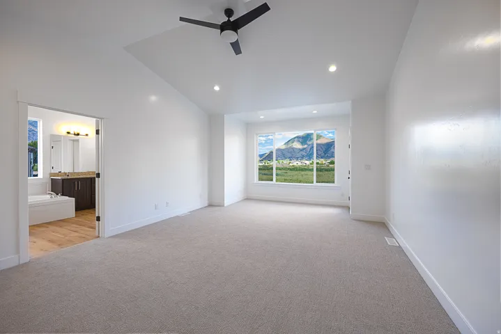 Spacious bedroom with vaulted ceiling, recessed lighting, and a modern ceiling fan