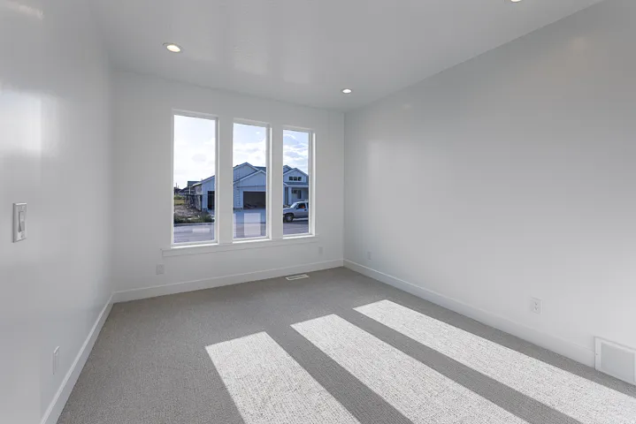 Neutral wall paint, recessed ceiling lighting, three pane windows, light grey carpeting, and white trim throughout