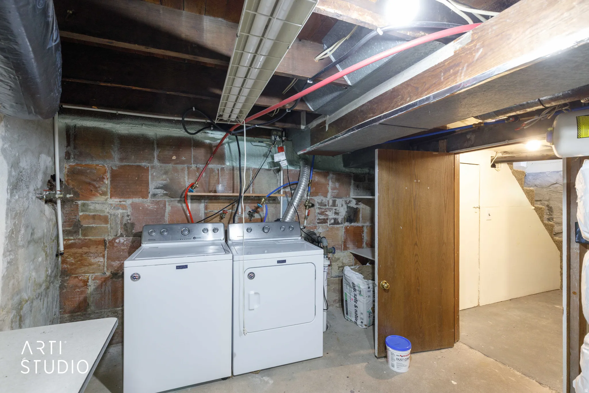 Exposed brick wall, concrete flooring, and exposed ceiling joists