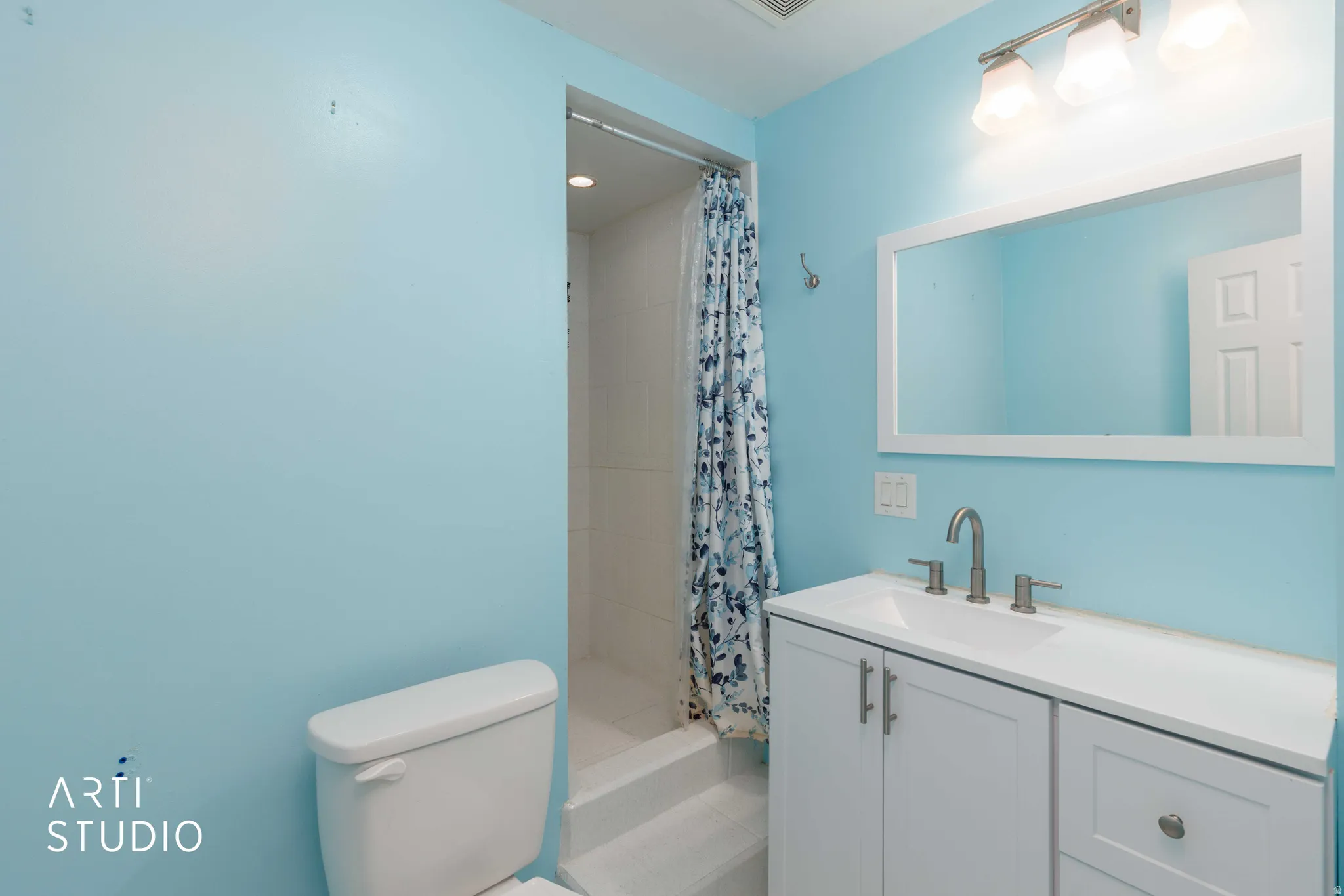 White vanity with brushed nickel hardware, integrated sink, and wall-mounted light fixture