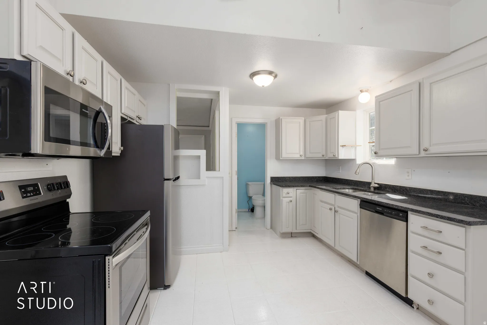 Kitchen featuring white cabinetry, dark countertops, stainless steel appliances, and a built-in microwave