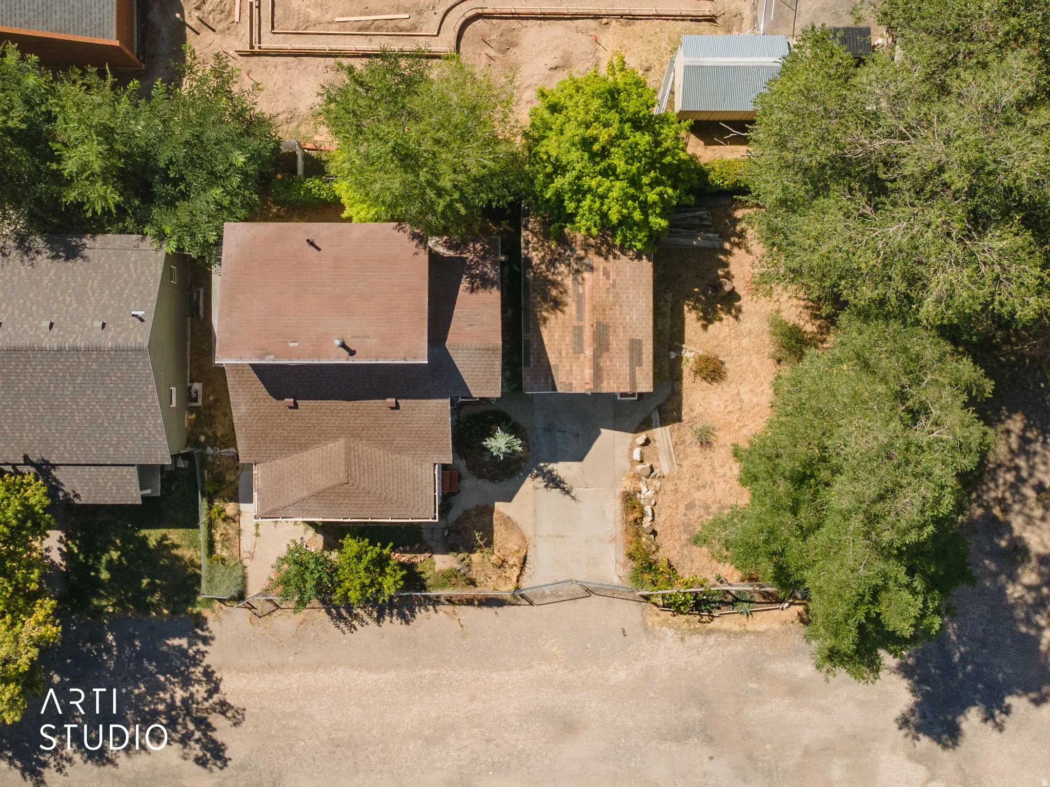 Aerial view of property featuring multiple structures, mature trees, and an asphalt driveway