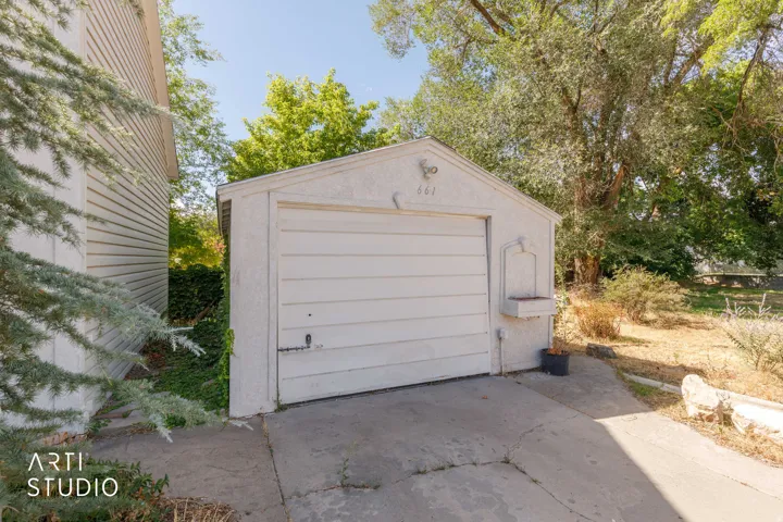 Detached garage with a paneled door and stucco exterior