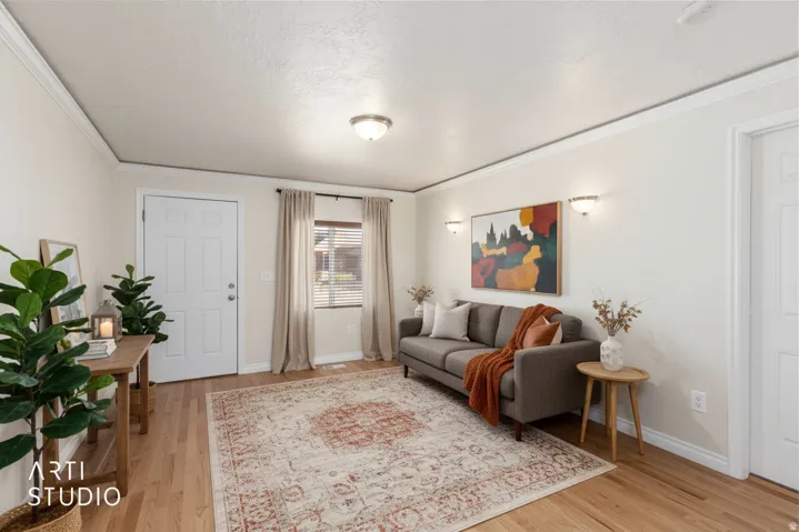 Wood-finish flooring, crown molding, wall-mounted sconces, and a multi-pane window with blinds. (photo is digitally staged with ai)