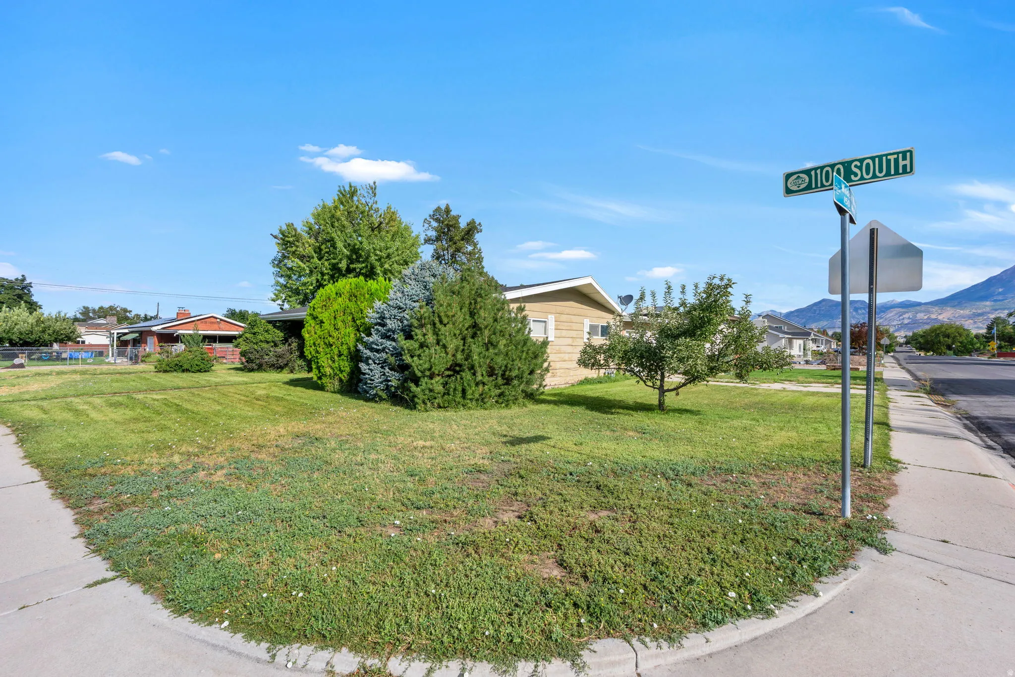 Expansive corner lot featuring a manicured lawn and mature trees