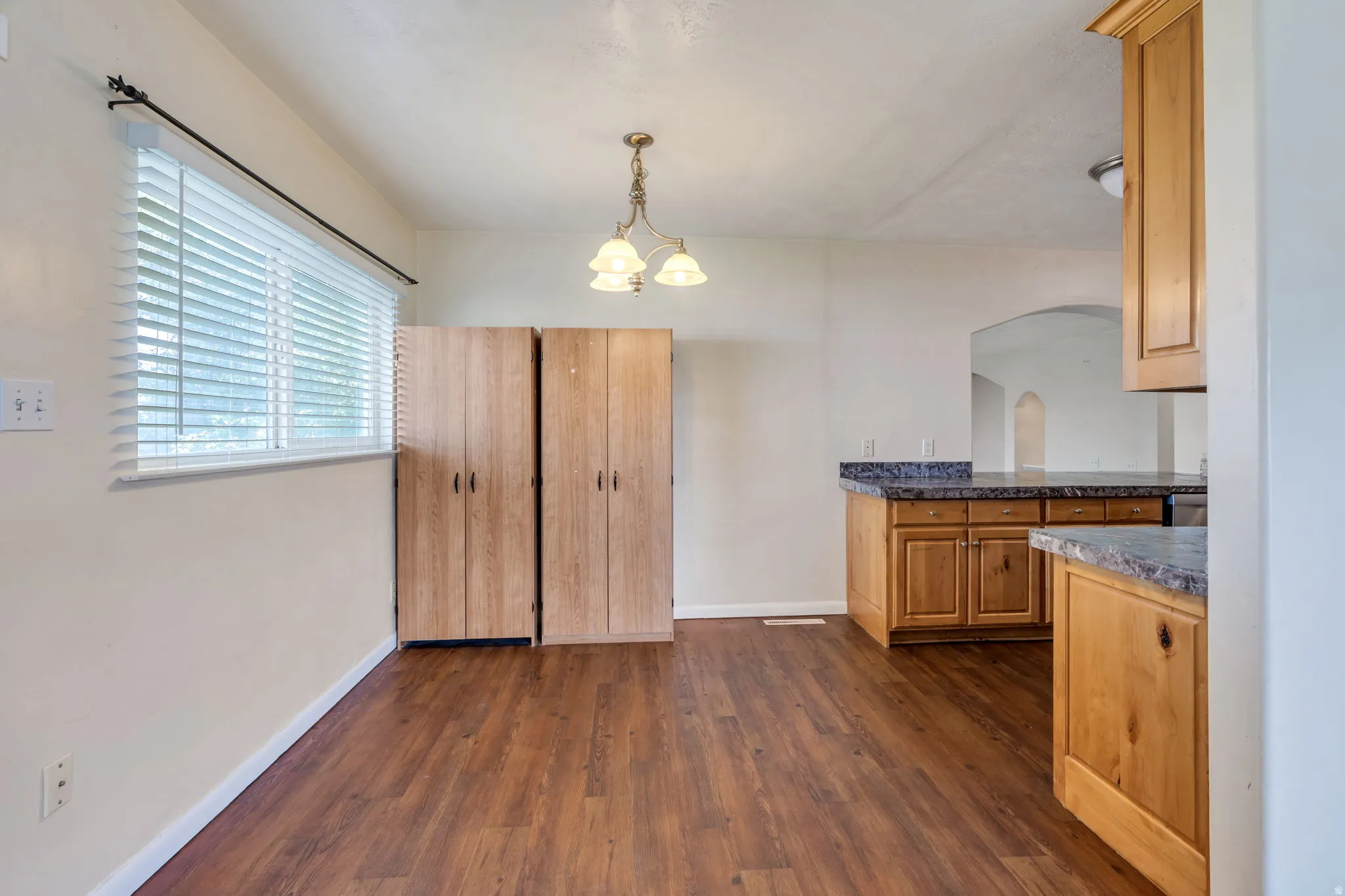 Wood-finish flooring throughout, light-toned walls, and a multi-pane window with horizontal blinds
