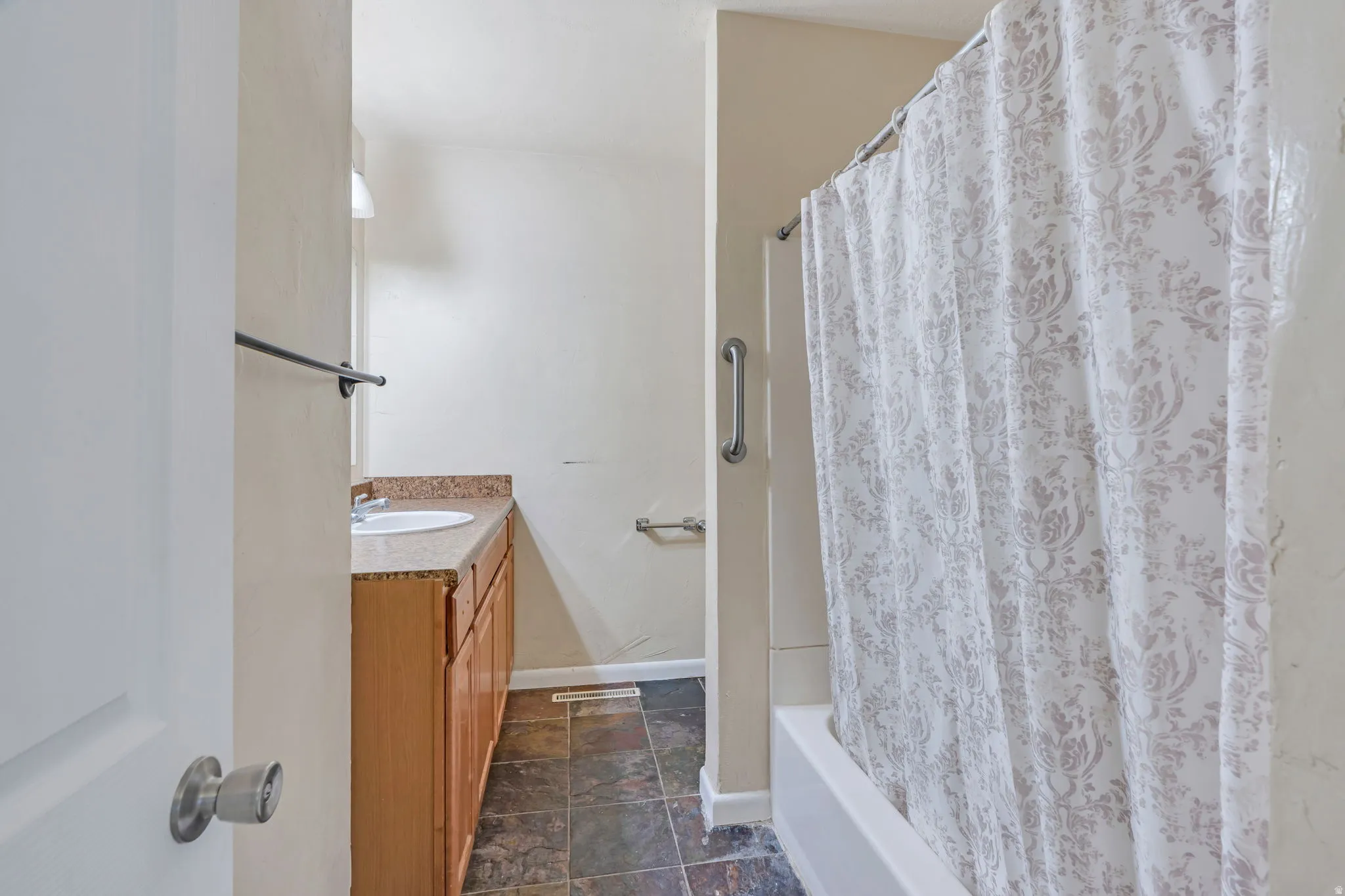 Bathroom featuring a single vanity with wood-finish cabinetry, a white basin sink, and a countertop