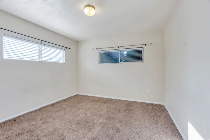 Carpeted room with multiple windows, horizontal blinds, and a ceiling-mounted light fixture