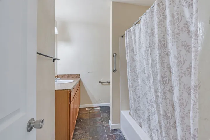 Bathroom featuring a single vanity with wood-finish cabinetry, a white basin sink, and a countertop