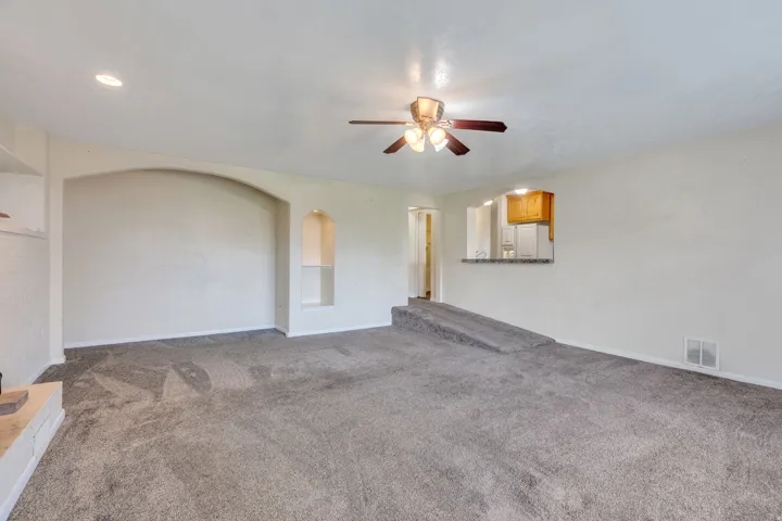Spacious room with gray carpet, recessed lighting, and a ceiling fan