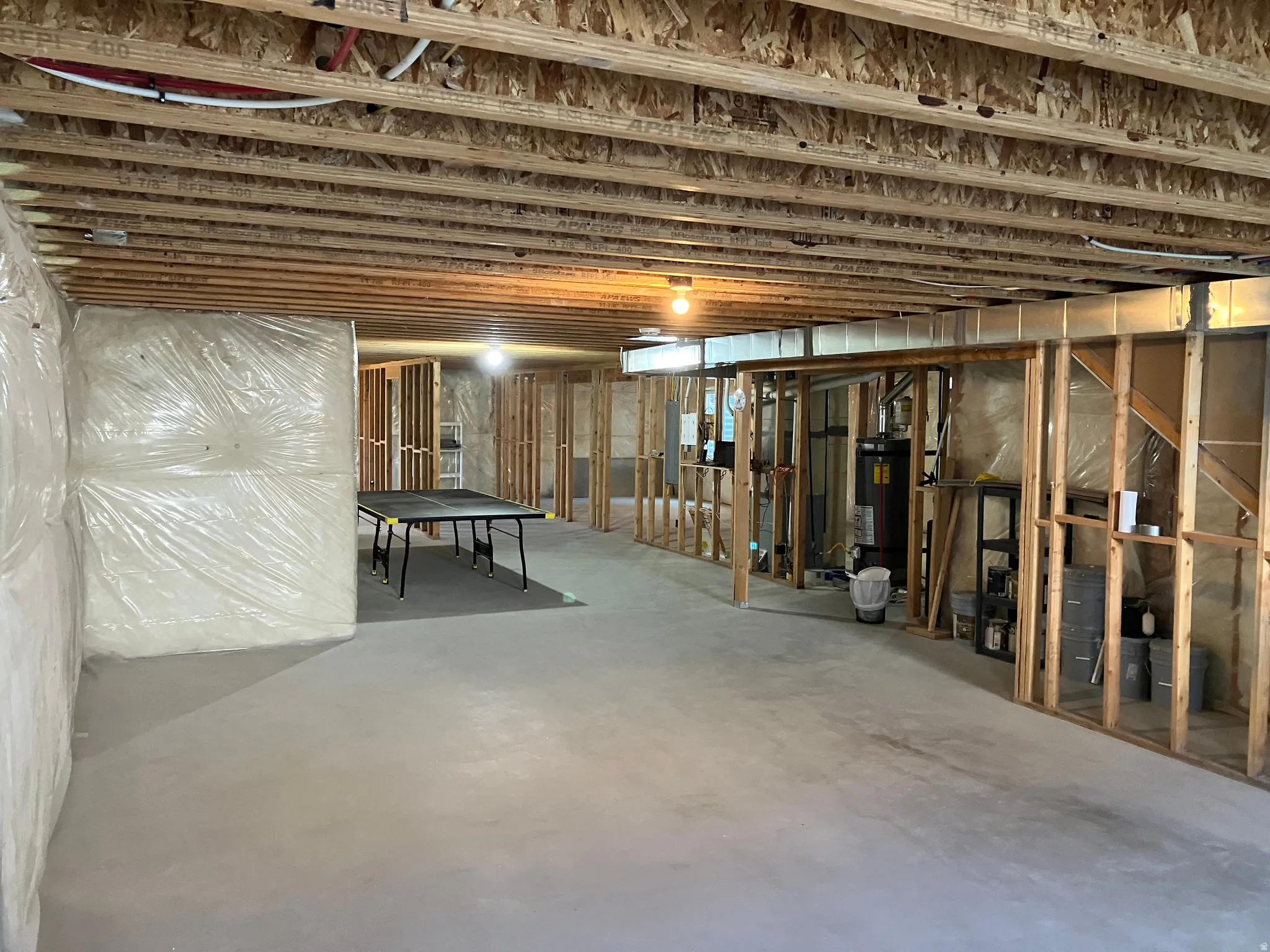Unfinished basement with exposed joists, concrete flooring, and framed interior walls