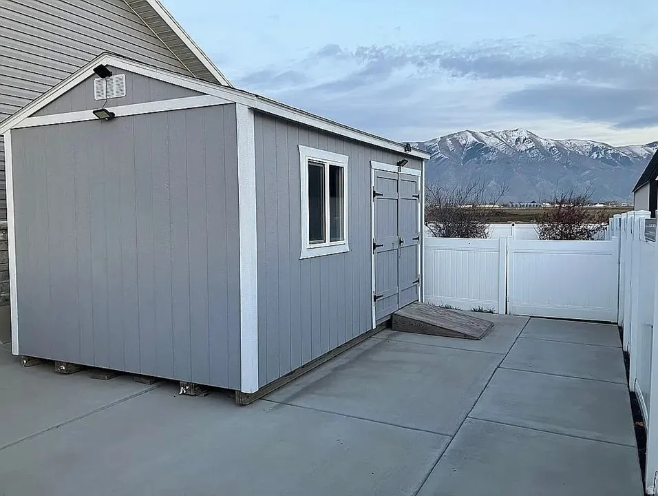 Detached shed with light gray siding, a single window, and double doors featuring black hardware