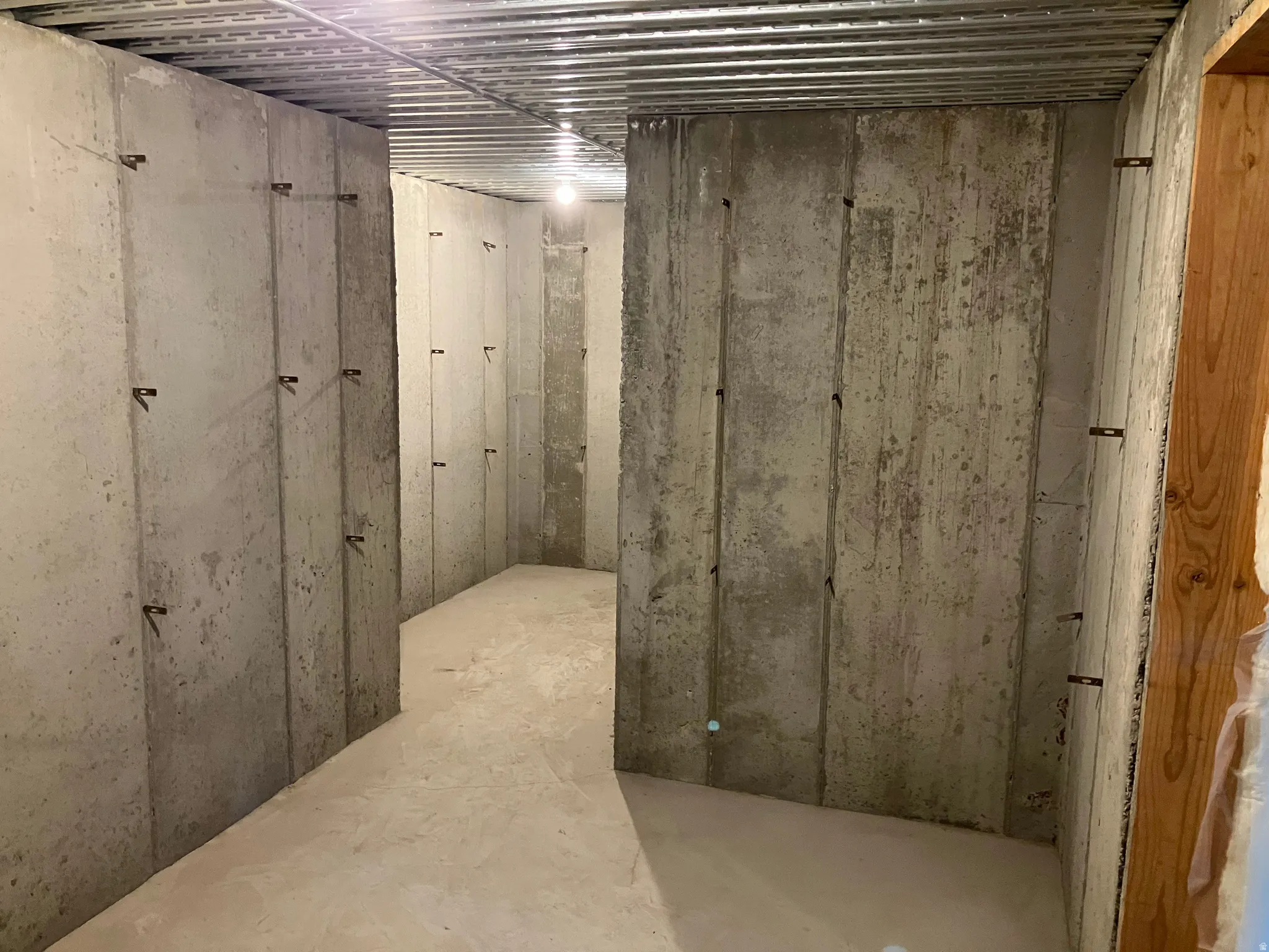 Unfinished concrete walls, concrete flooring, and exposed metal ceiling beams